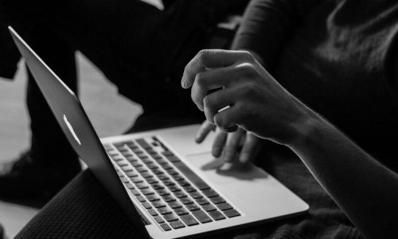 grayscale photo of person using MacBook